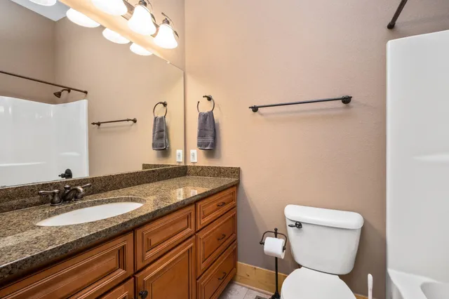 a bathroom with a granite countertop toilet sink and mirror