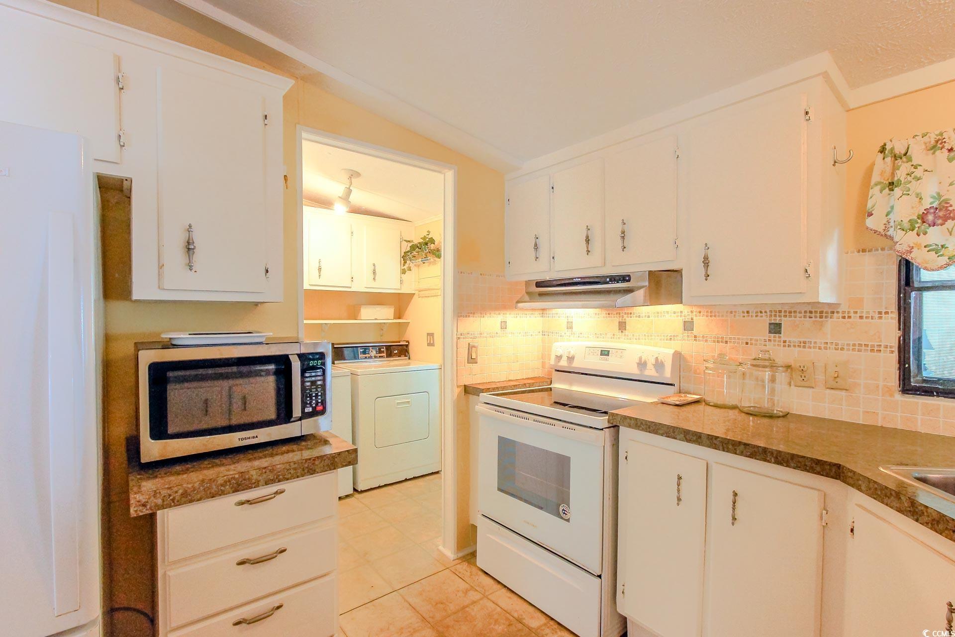 163 Crooked Island Circle Murrells Inlet, SC 29576 - Photo 13 of 40 Kitchen featuring white appliances, backsplash, white cabinets, light tile patterned floors, and vaulted ceiling