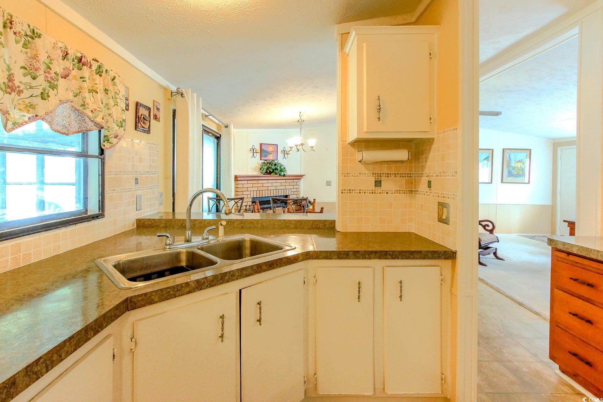 163 Crooked Island Circle Murrells Inlet, SC 29576 - Photo 14 of 40 Kitchen with backsplash, white cabinetry, a chandelier, a textured ceiling, and dark countertops