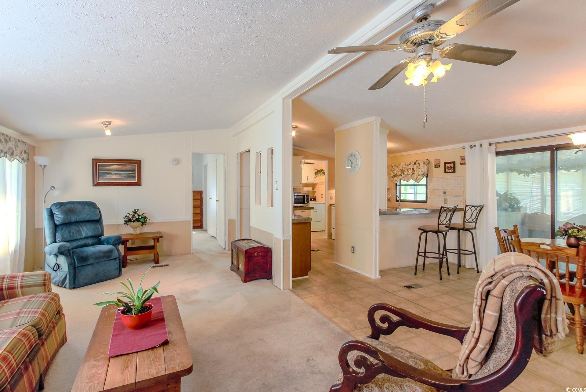 163 Crooked Island Circle Murrells Inlet, SC 29576 - Photo 2 of 40 Living room with light carpet, a ceiling fan, crown molding, light tile patterned floors, and a textured ceiling