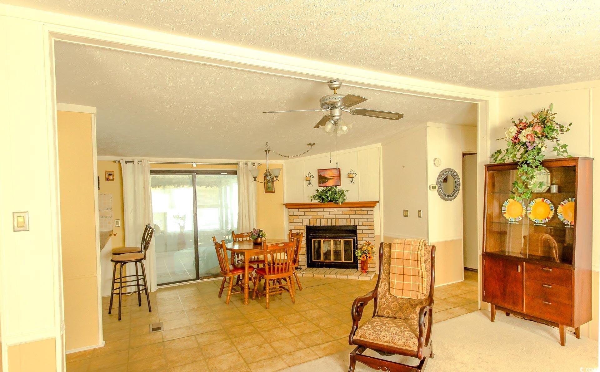 163 Crooked Island Circle Murrells Inlet, SC 29576 - Photo 3 of 40 Sitting room featuring a textured ceiling, a fireplace, a ceiling fan, and tile patterned flooring