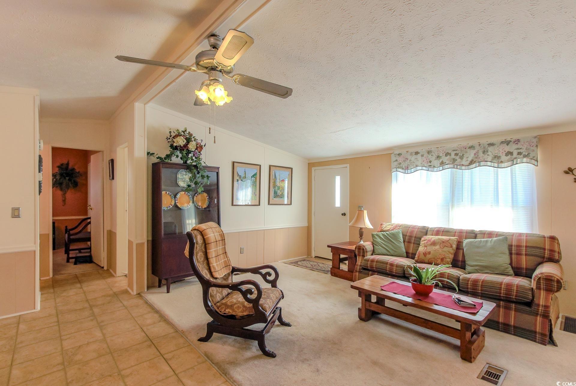 163 Crooked Island Circle Murrells Inlet, SC 29576 - Photo 5 of 40 Living room with a textured ceiling, vaulted ceiling, wainscoting, tile patterned floors, and ornamental molding