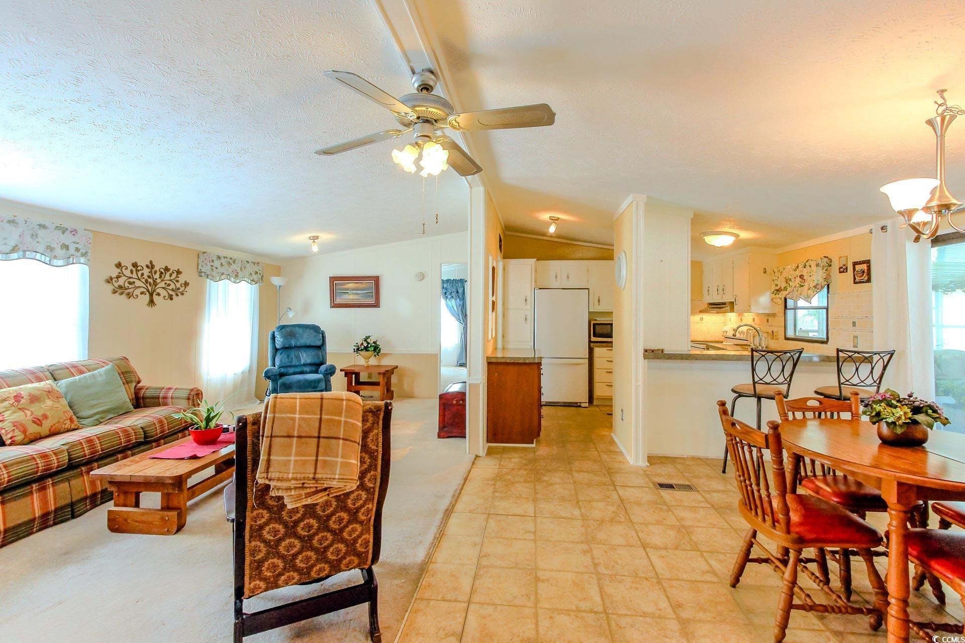 163 Crooked Island Circle Murrells Inlet, SC 29576 - Photo 8 of 40 Living room featuring healthy amount of natural light, lofted ceiling, a chandelier, a ceiling fan, and a textured ceiling