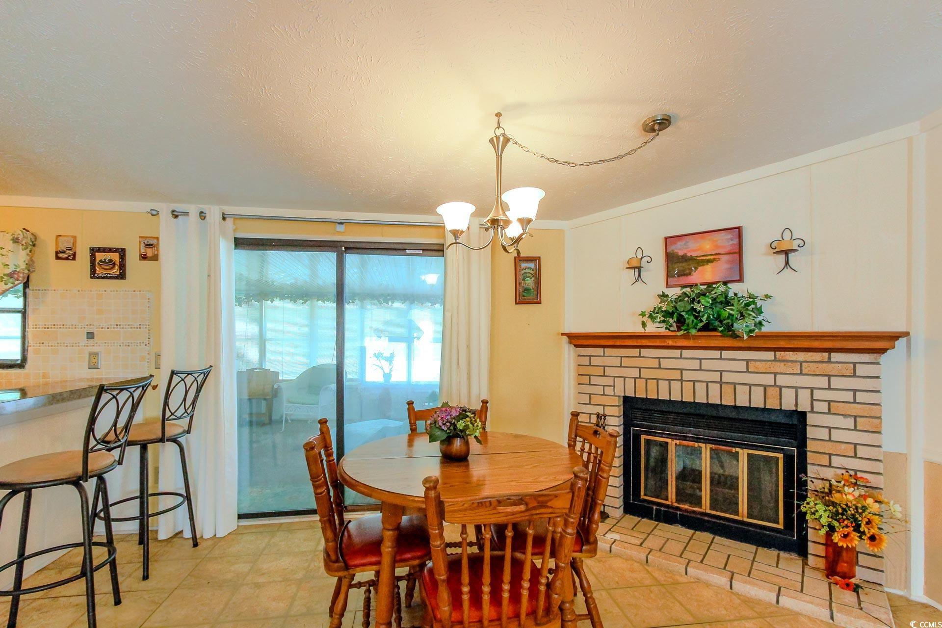 163 Crooked Island Circle Murrells Inlet, SC 29576 - Photo 9 of 40 Tiled dining room featuring a brick fireplace, a textured ceiling, a chandelier, and ornamental molding