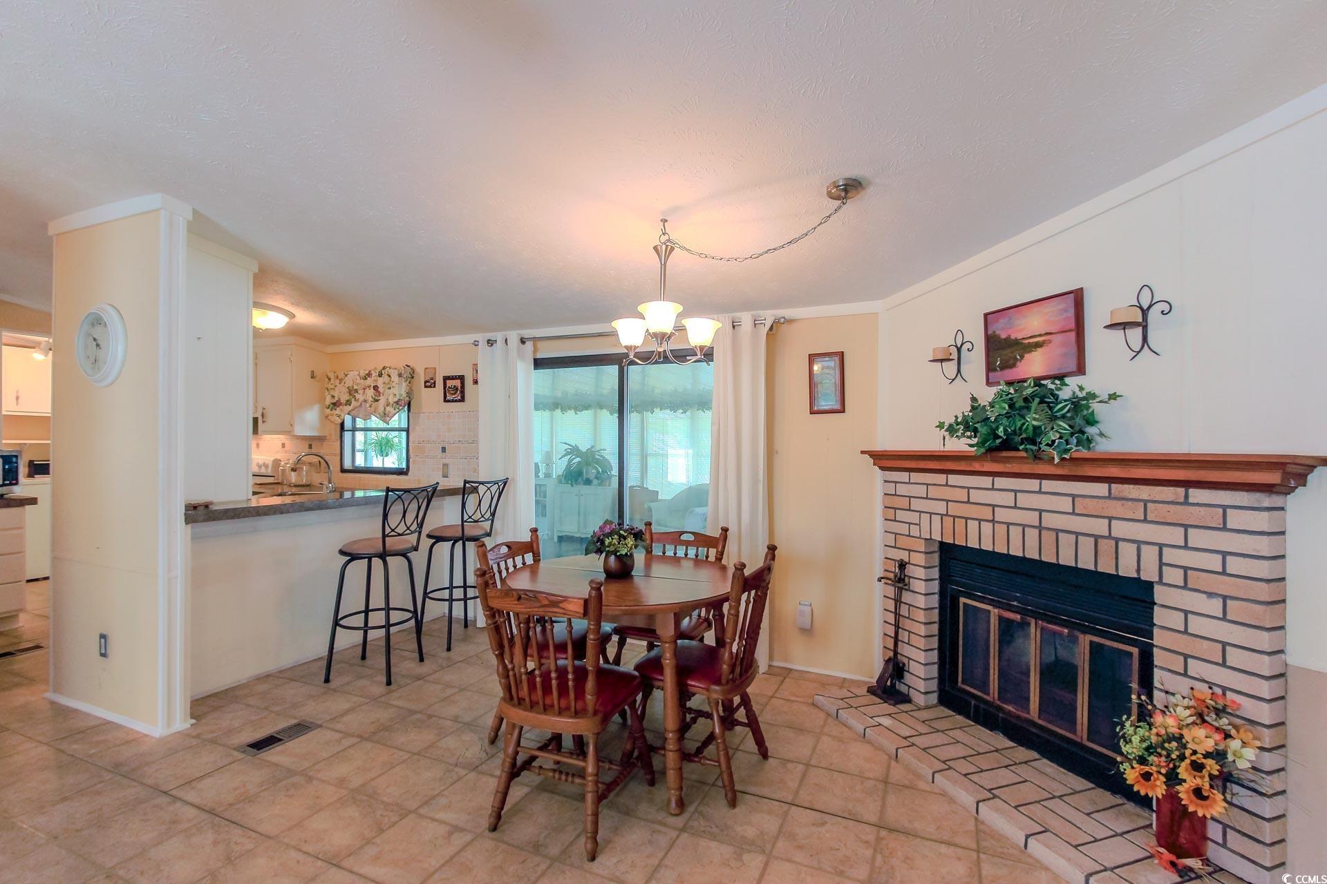 163 Crooked Island Circle Murrells Inlet, SC 29576 - Photo 10 of 40 Dining space featuring a fireplace, crown molding, and a chandelier