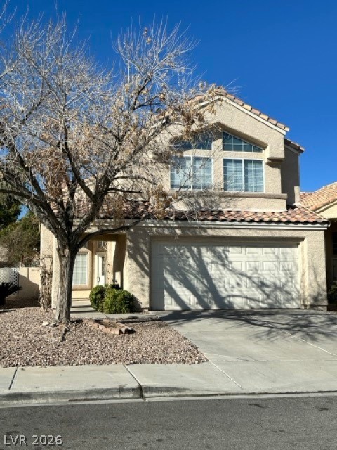 View of front of home with a garage, stucco siding, a tile roof, and driveway