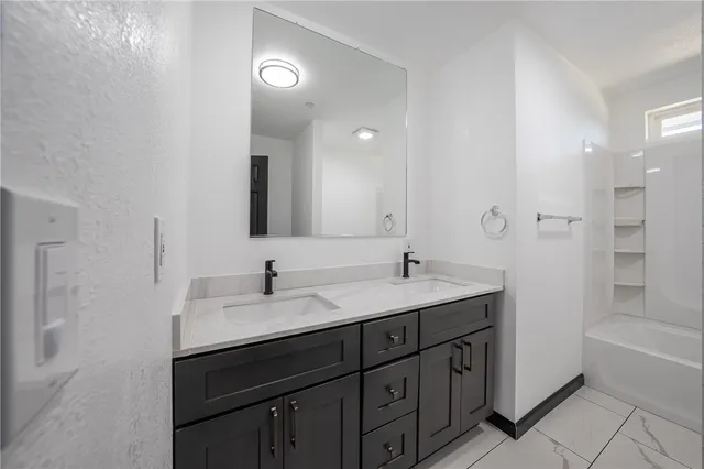 a bathroom with a sink double vanity granite tub shower and a mirror