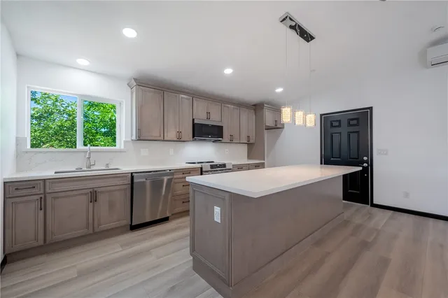 a large kitchen with stainless steel appliances granite countertop a sink a stove a refrigerator and island with wooden floor