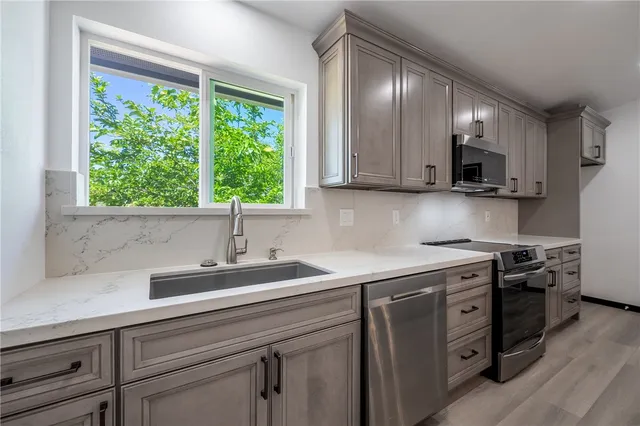 a kitchen with stainless steel appliances granite countertop a sink a stove and a microwave