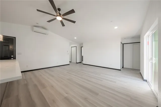 an empty room with wooden floor and a ceiling fan