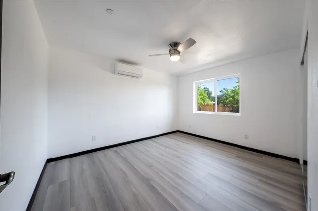 an empty room with wooden floor ceiling fan and windows