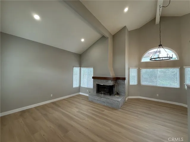 an empty room with wooden floor fireplace and window