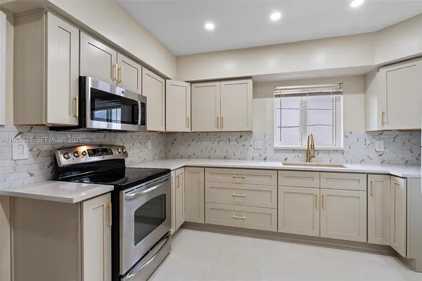 a kitchen with granite countertop white cabinets stainless steel appliances and a sink