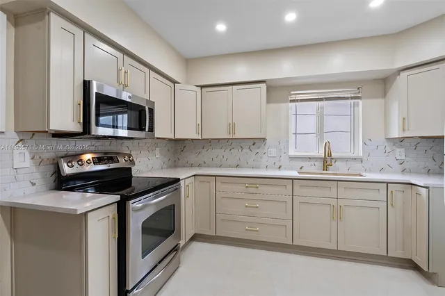 a kitchen with granite countertop white cabinets stainless steel appliances and a sink