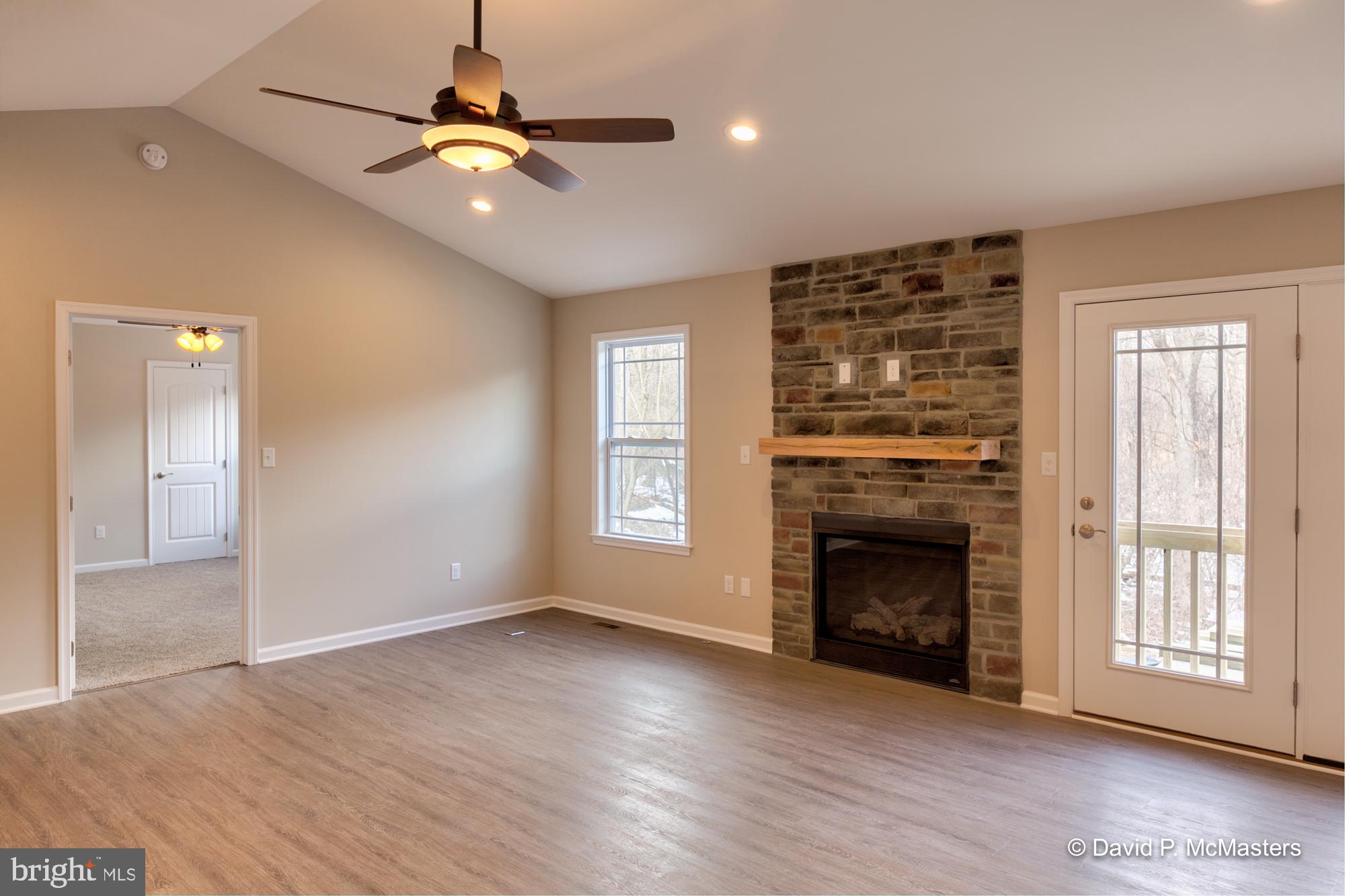 194 Dimension Road Inwood, WV 25428 - Photo 16 of 26 an empty room with windows fireplace and a chandelier fan