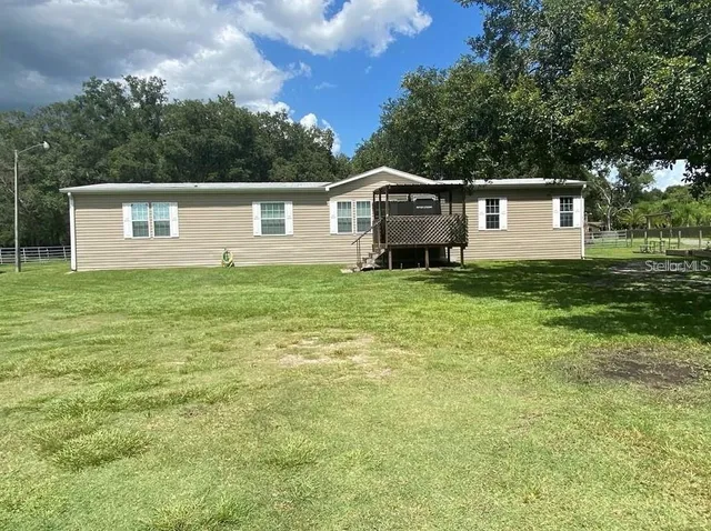 a house that is sitting in the grass with large trees