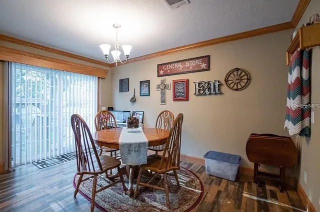 a view of a dining room with furniture a chandelier and a window