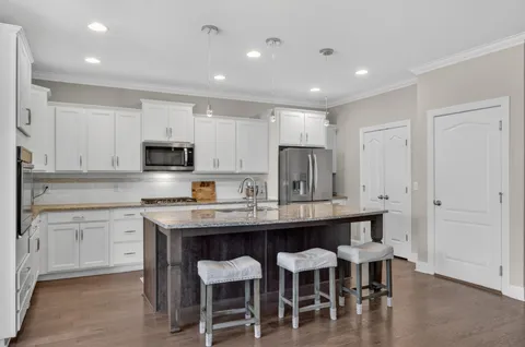 a kitchen with stainless steel appliances granite countertop a table chairs microwave and cabinets