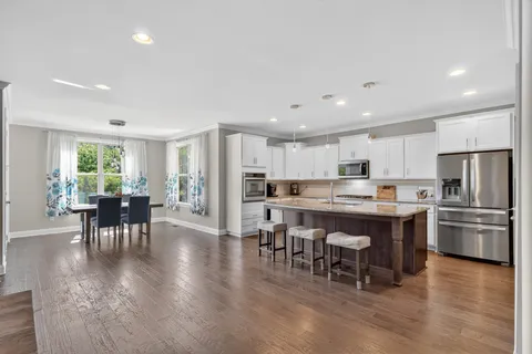 a kitchen with kitchen island a dining table chairs and wooden floor
