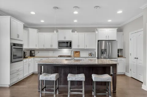 a kitchen with stainless steel appliances granite countertop a table chairs microwave and sink