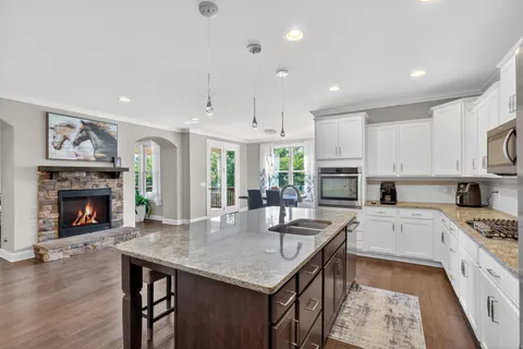 a kitchen with granite countertop kitchen island a stove a sink a refrigerator and a dining table with wooden floor