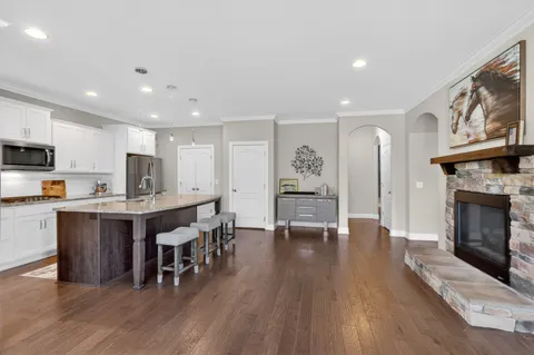 a open kitchen with stainless steel appliances granite countertop a stove top oven a sink dishwasher a dining table and chairs with wooden floor