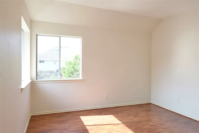 an empty room with wooden floor and a window