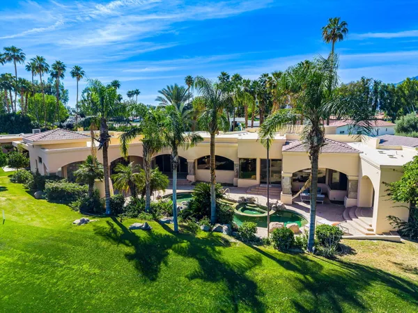 a view of a white house with a yard and palm trees