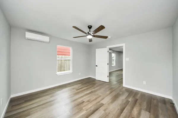 an empty room with wooden floor and ceiling fan