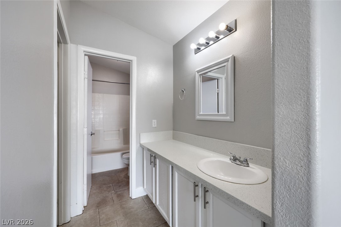 5985 High Steed Street, Unit 101 Henderson, NV 89011 - Photo 19 of 38 A well-lit bathroom with a spacious vanity, sleek faucet, and classic tiled flooring.