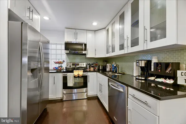 a kitchen with stainless steel appliances granite countertop a refrigerator a stove a sink and a microwave