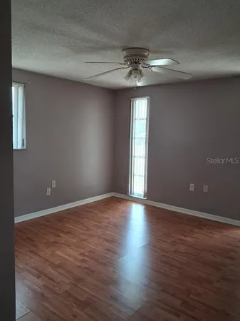 a view of an empty room with a window and wooden floor