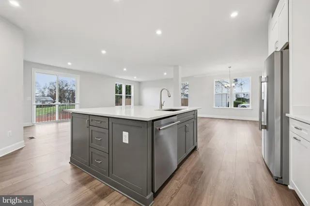 a kitchen with kitchen island granite countertop a refrigerator a sink dishwasher and wooden cabinets with wooden floor