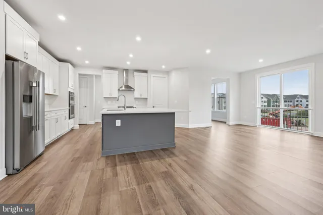 a living room with stainless steel appliances kitchen island wooden floors and center island