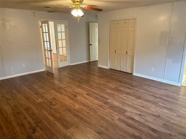 a view of an empty room with wooden floor and window