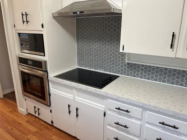 a kitchen with granite countertop white cabinets and stainless steel appliances