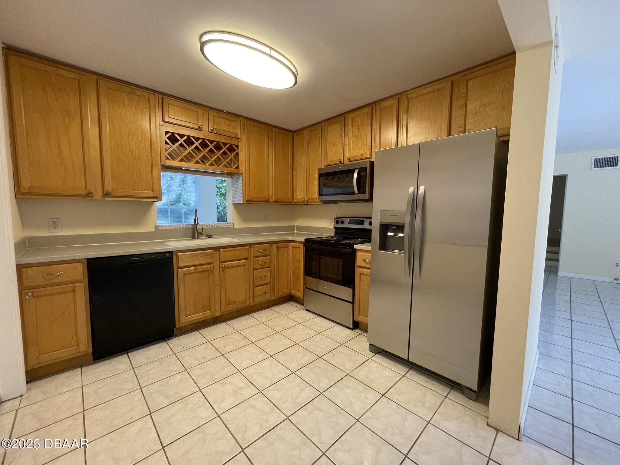 525 Tarragona Way Daytona Beach, FL 32114 - Photo 12 of 47 a kitchen with stainless steel appliances a refrigerator sink and cabinets