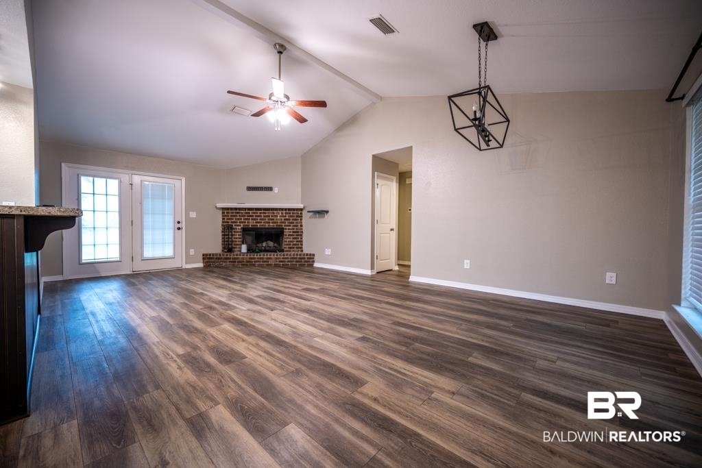15874 Carver Road, Unit C Foley, AL 36535 - Photo 9 of 18 Unfurnished living room with dark wood-type flooring, vaulted ceiling, a brick fireplace, and ceiling fan