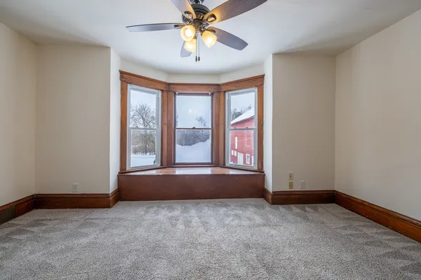 a view of an empty room with window and chandelier fan