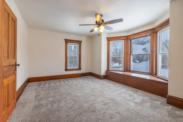a view of an empty room with window and chandelier fan