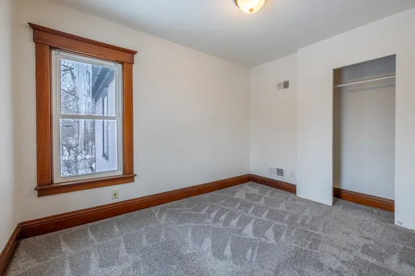 a view of an empty room with window and closet