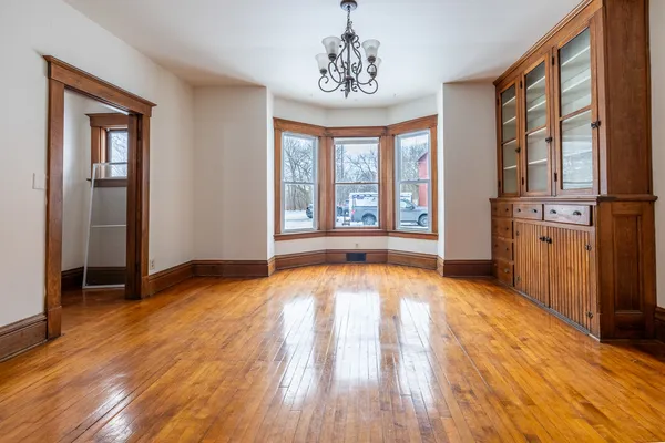 a view of an empty room with a window and wooden floor