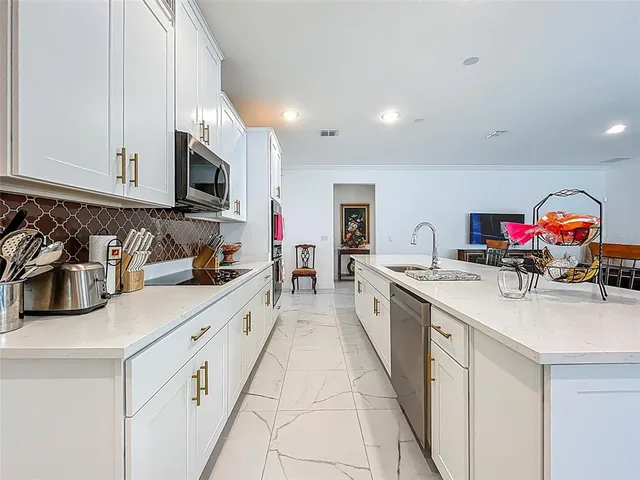 a kitchen with stainless steel appliances granite countertop a sink dishwasher and white cabinets with wooden floor