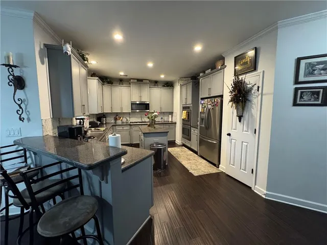 a kitchen with stainless steel appliances kitchen island granite countertop a table chairs refrigerator and sink