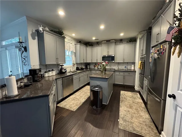 a kitchen with granite countertop a refrigerator a sink a stove a microwave and island