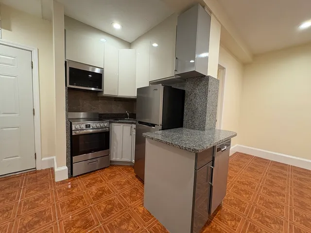 a kitchen with stainless steel appliances granite countertop a stove a refrigerator and a sink