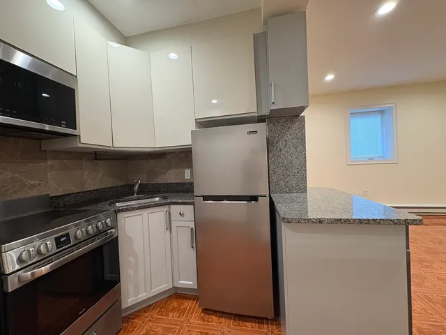 a kitchen with stainless steel appliances granite countertop a refrigerator a stove and a microwave