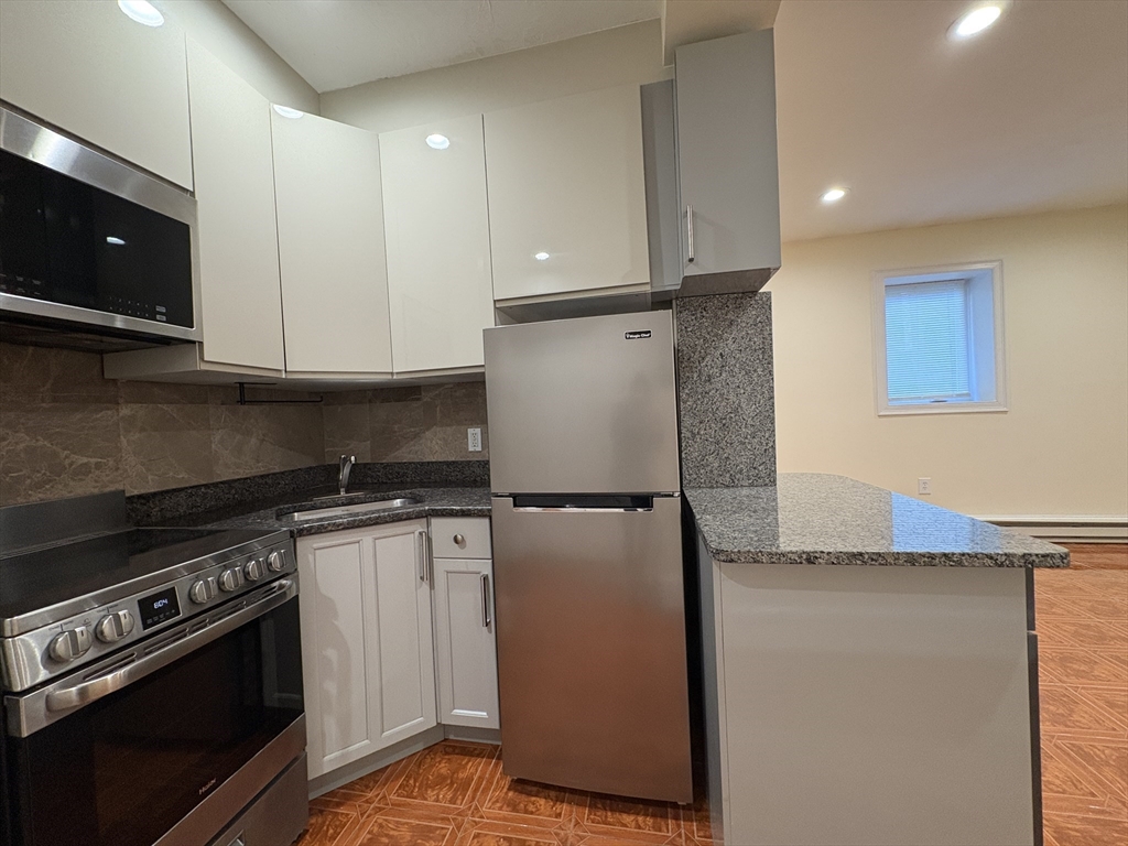 69 Babcock Street, Unit 7 Brookline, MA 02446 - Photo 6 of 9 a kitchen with stainless steel appliances granite countertop a refrigerator a stove and a microwave
