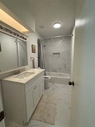 a bathroom with a granite countertop sink a toilet and shower