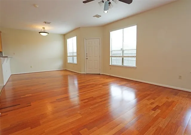 an empty room with wooden floor and windows